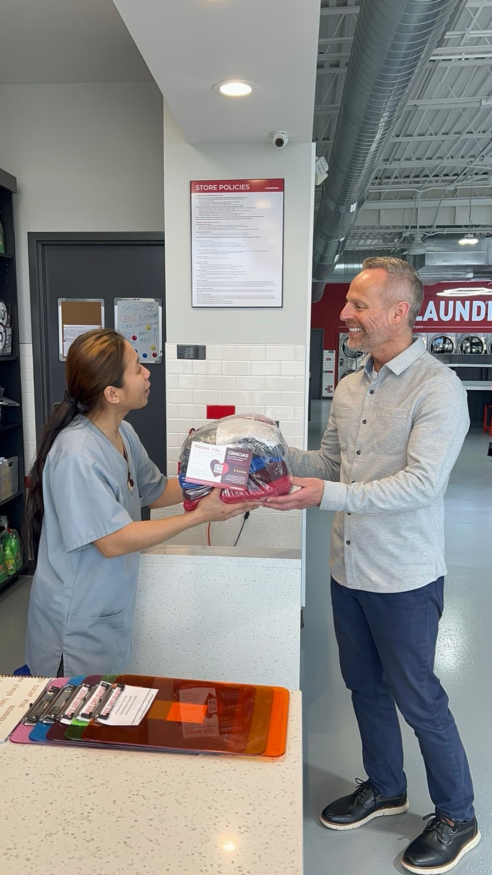 A team member handing a customer his finished, wrapped laundry at the counter